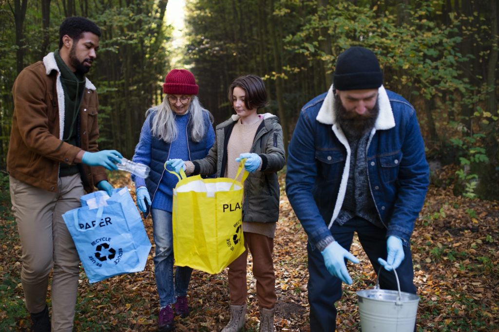 Diverse group of volunteers cleaning up forest from waste, community service concept