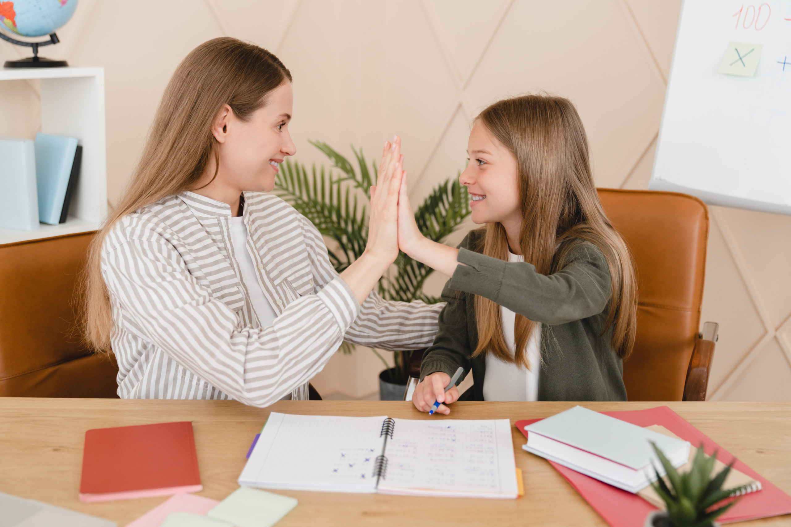 Tutor nanny helping daughter student with homework,exam, new topic giving high five at home school.